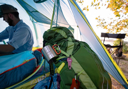 KLIPP Carabiner Mug 1.0 attached to a green backpack inside a blue camping tent.