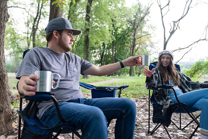 People using KLIPP Carabiner Mug 1.0 with orange carabiner handle outdoors, enjoying beverages in nature.