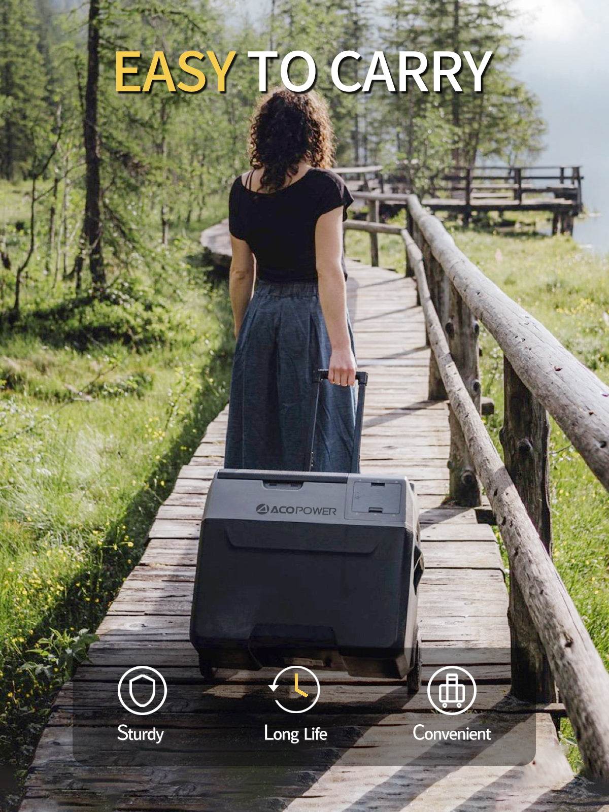 Portable solar fridge freezer being wheeled by a person on a forest boardwalk, emphasizing ease of transport and durability.