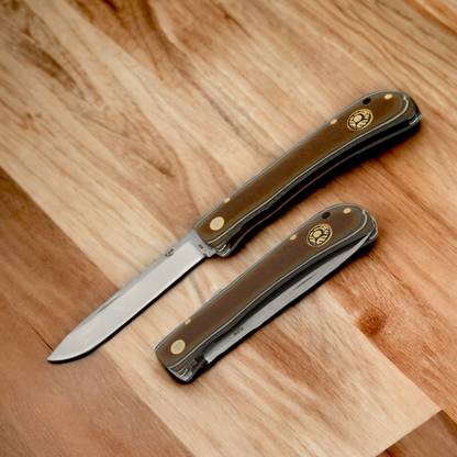 Kam Knife PR77 with 4116 steel blade and micarta handle, black lock pocket knife on wooden surface.