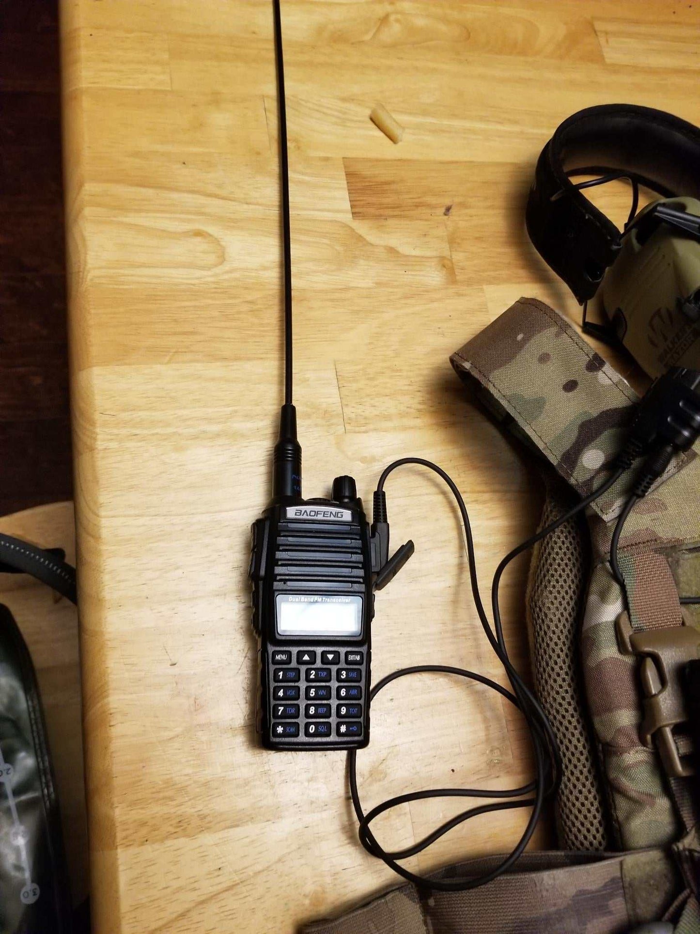 SMC cable connecting Baofeng radio to electronic earmuffs for communication.