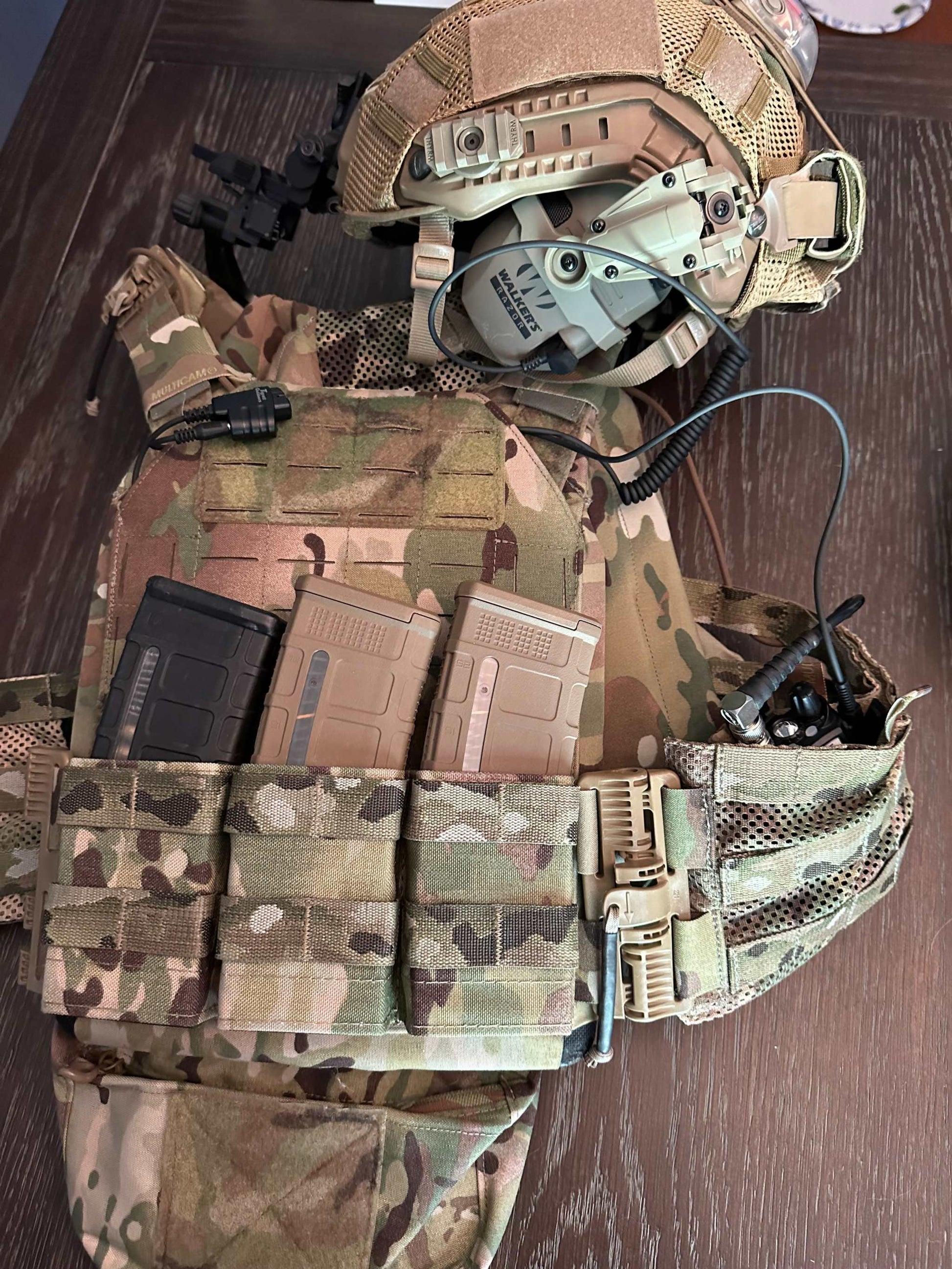 SMC Shoot, Move, Communicate cable connected to tactical gear and electronic earmuffs.