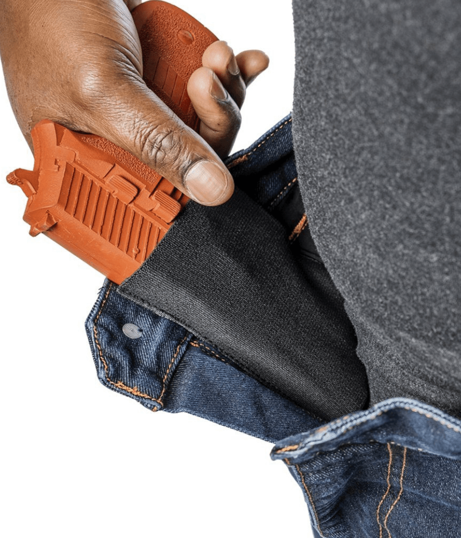 Asset Tactical Jeans showcasing concealed carry pocket with orange training pistol.