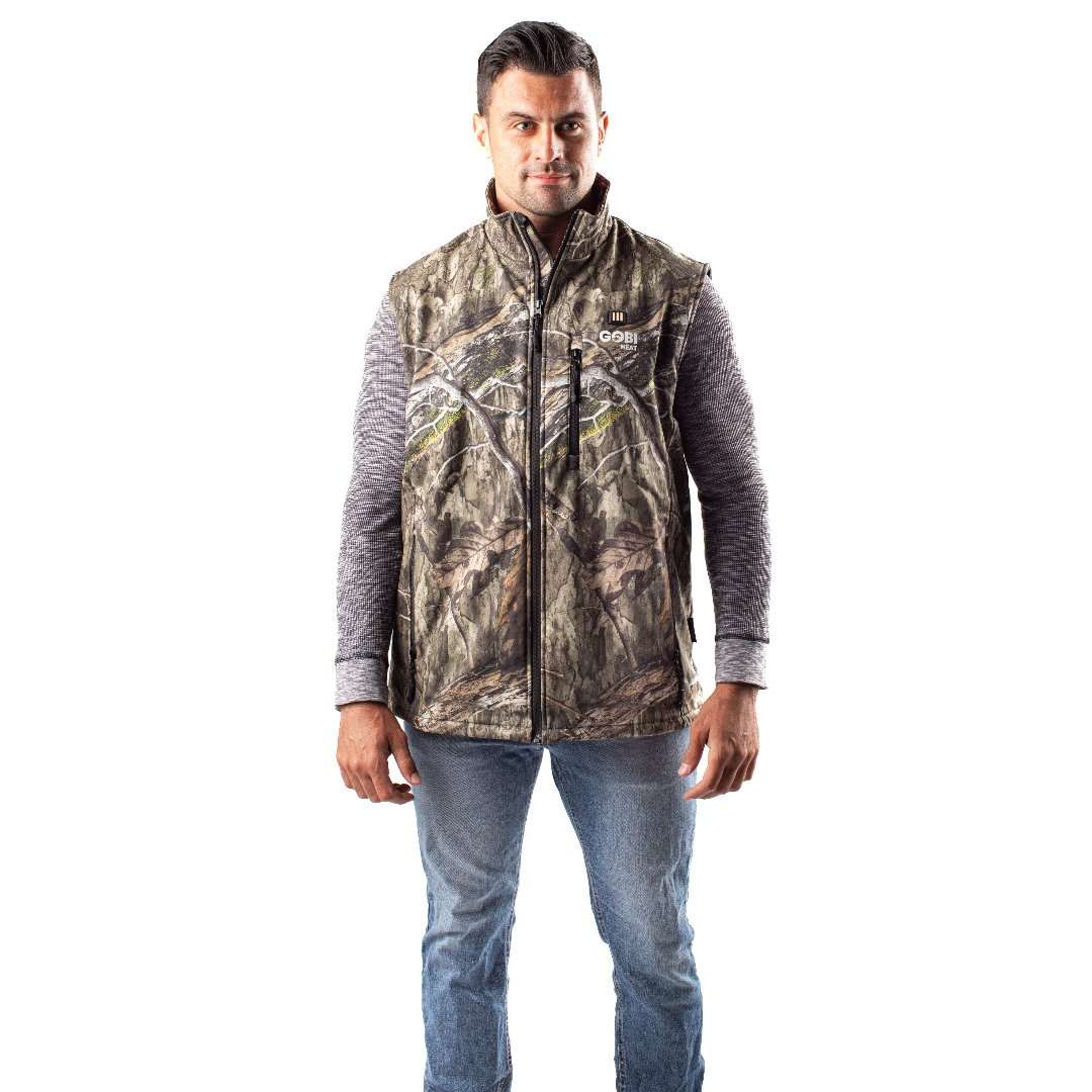 Colorado Mens Heated Hunting Vest-Mossy Oak Camo with fleece, polyester, and heating elements, modeled by a person standing.