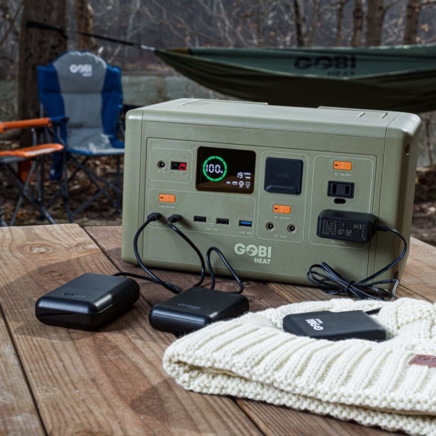 CORE 614W Portable Power Station on wooden table, powering multiple devices outdoors, featuring LCD display and various ports for versatile charging.