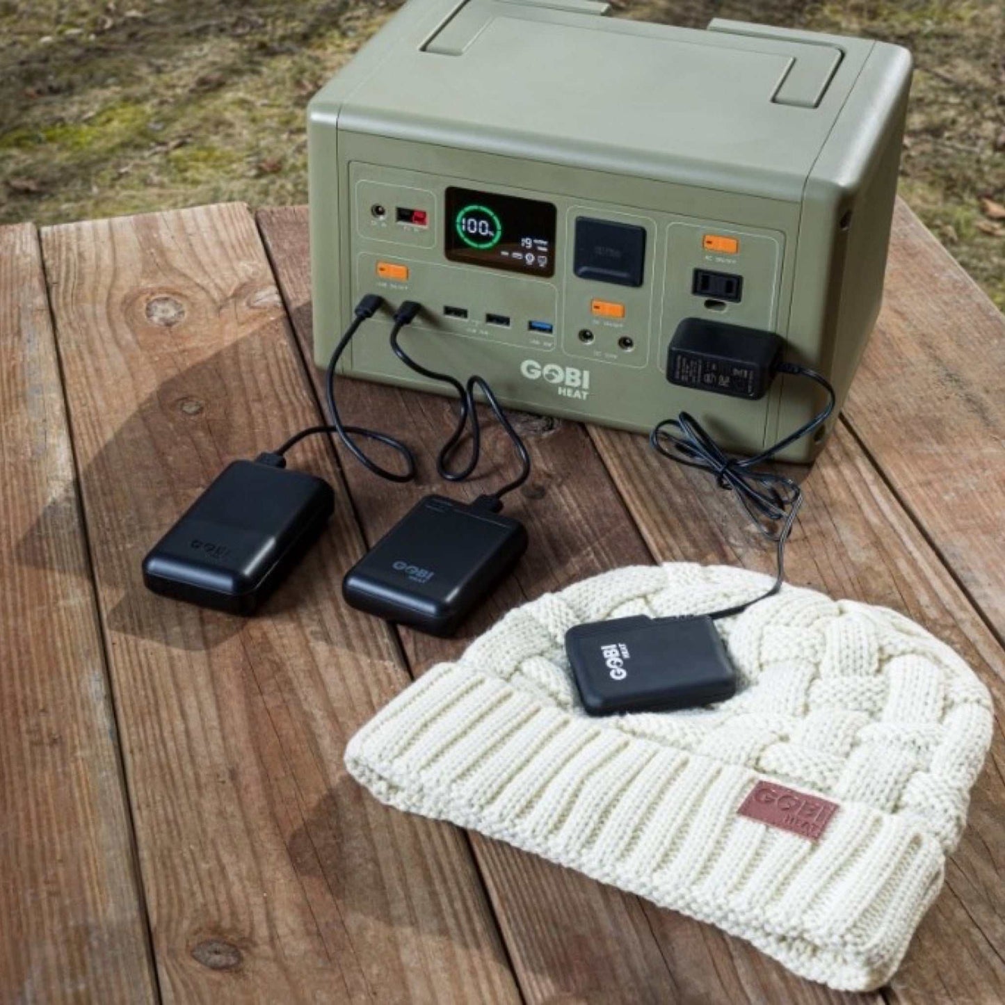 CORE 614W Portable Power Station for camping and emergencies, charging multiple devices on a wooden table outdoors.