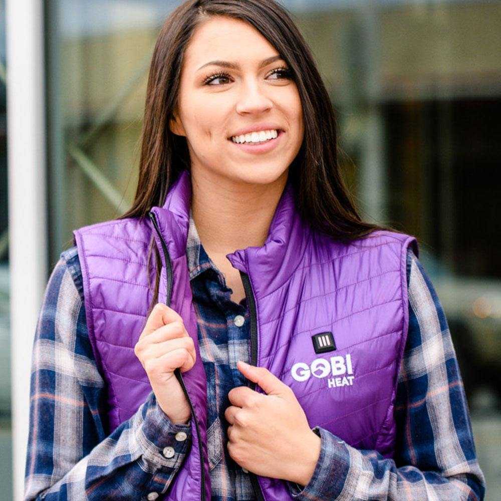 Woman wearing Dune Heated Vest in Plum color, featuring lightweight, abrasion-resistant nylon and conductive thread heating elements.