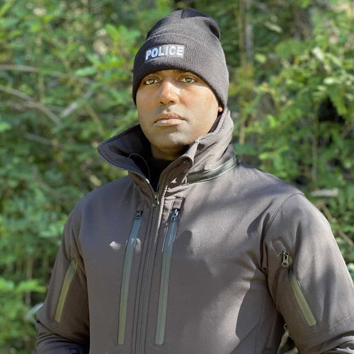 Man wearing black Equinoxx Police Beanie in outdoor setting, showing reflective logo.