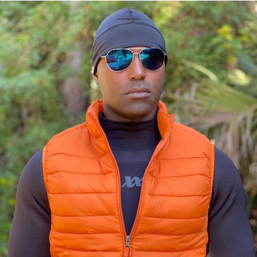 Man wearing an Equinoxx Watch Cap Beanie outdoors, paired with an orange vest and sunglasses.