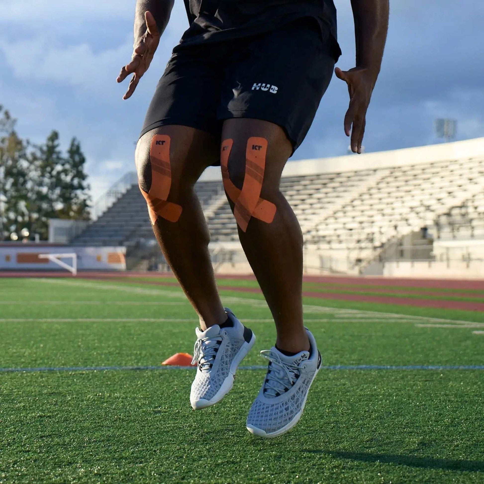 Man using KT Tape Pro® during outdoor workout on athletic field.