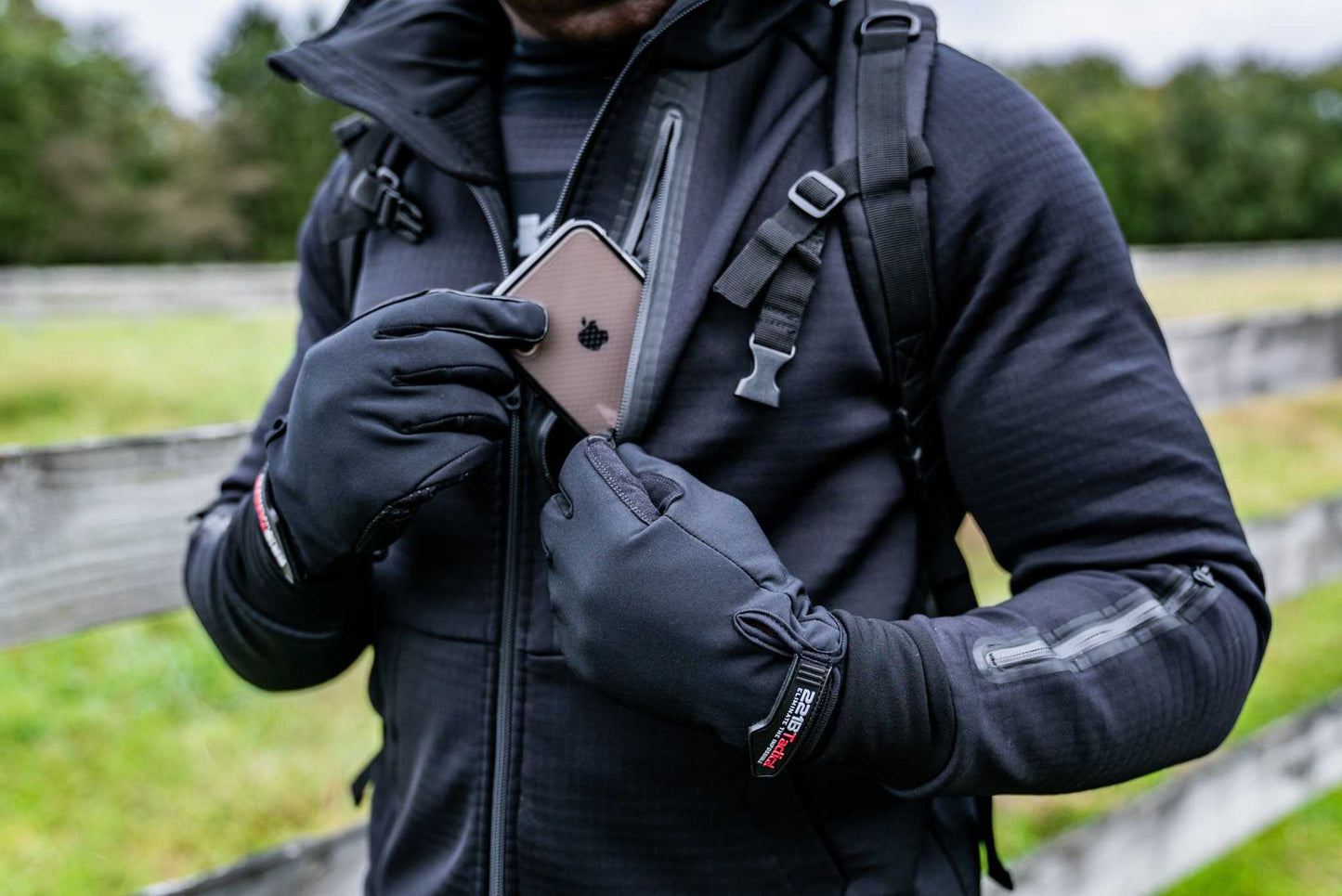 Person wearing Rendition Jacket Elite outdoors, demonstrating its smart pocket functionality with integrated technology and durable design.