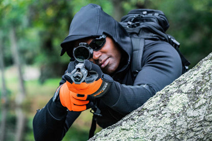 Man wearing Rendition Jacket Elite aiming a rifle in outdoor setting.