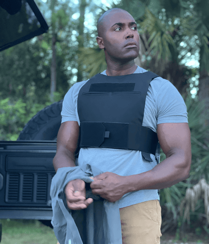 Stealth low visibility concealed body armor plate carrier worn by a person in outdoor setting.