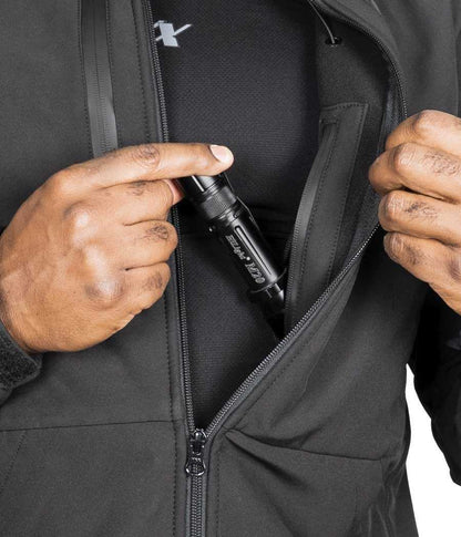 Man with flashlight in pocket of Tradecraft Tactical Jacket 2.0, featuring waterproof zippers.