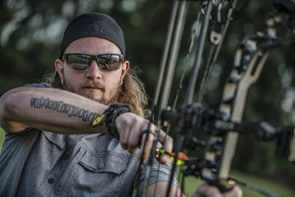 Man wearing lifestyle sunglasses while holding a bow, showcasing durable and stylish eyewear.