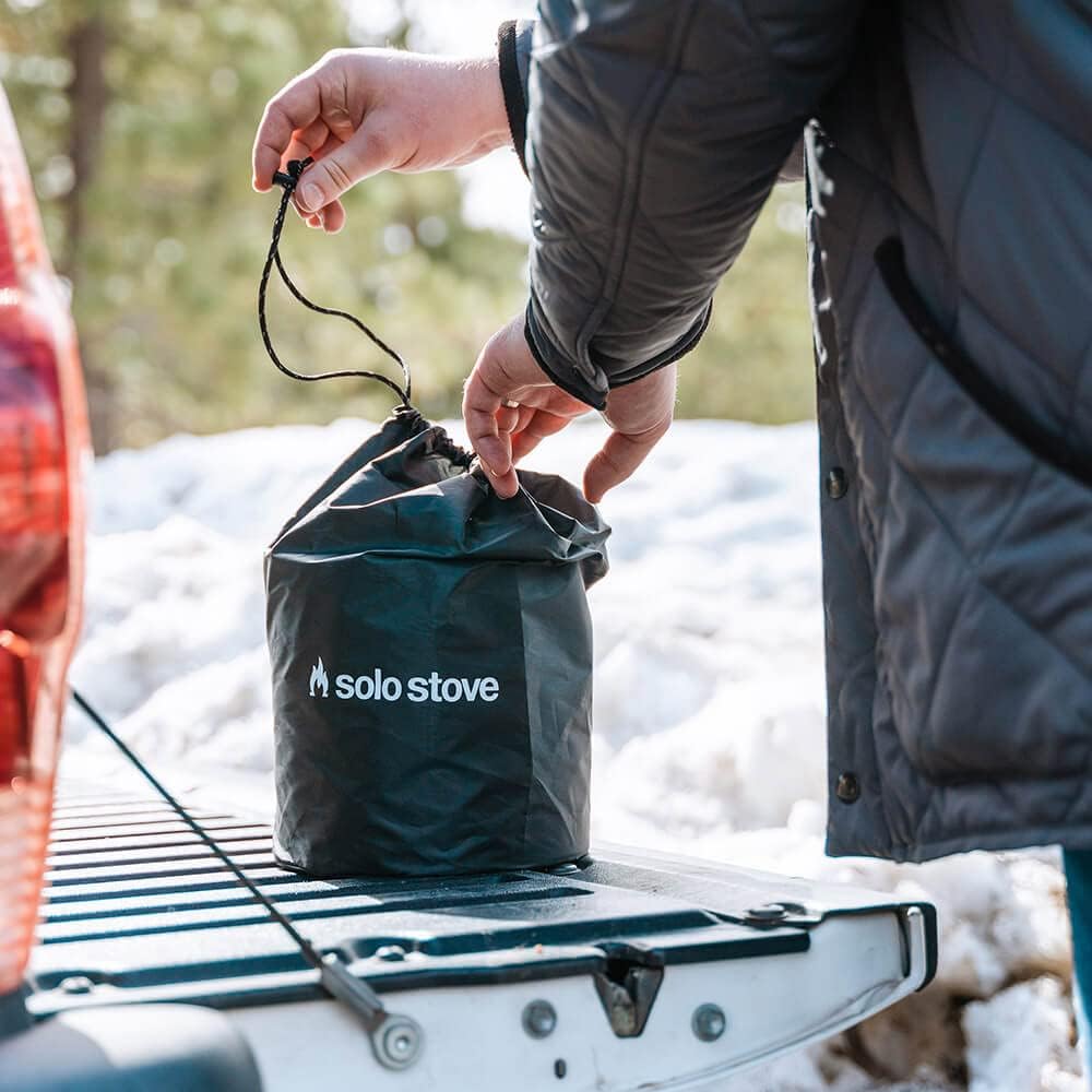 Portable camping stove in a carry bag on a vehicle for outdoor cooking and backpacking adventures.